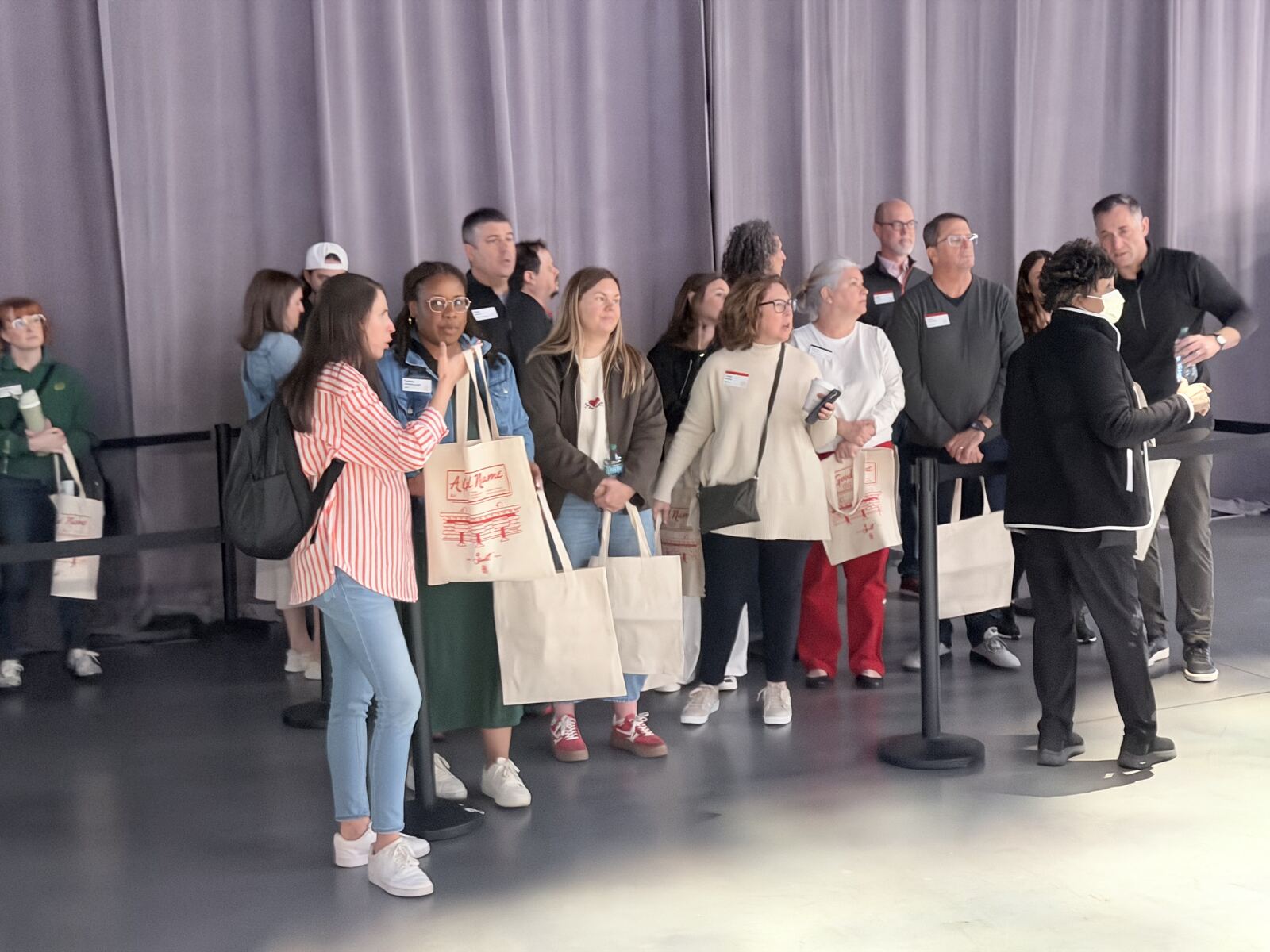 Diverse crowd of attendees at a corporate event holding branded tote bags with printed designs