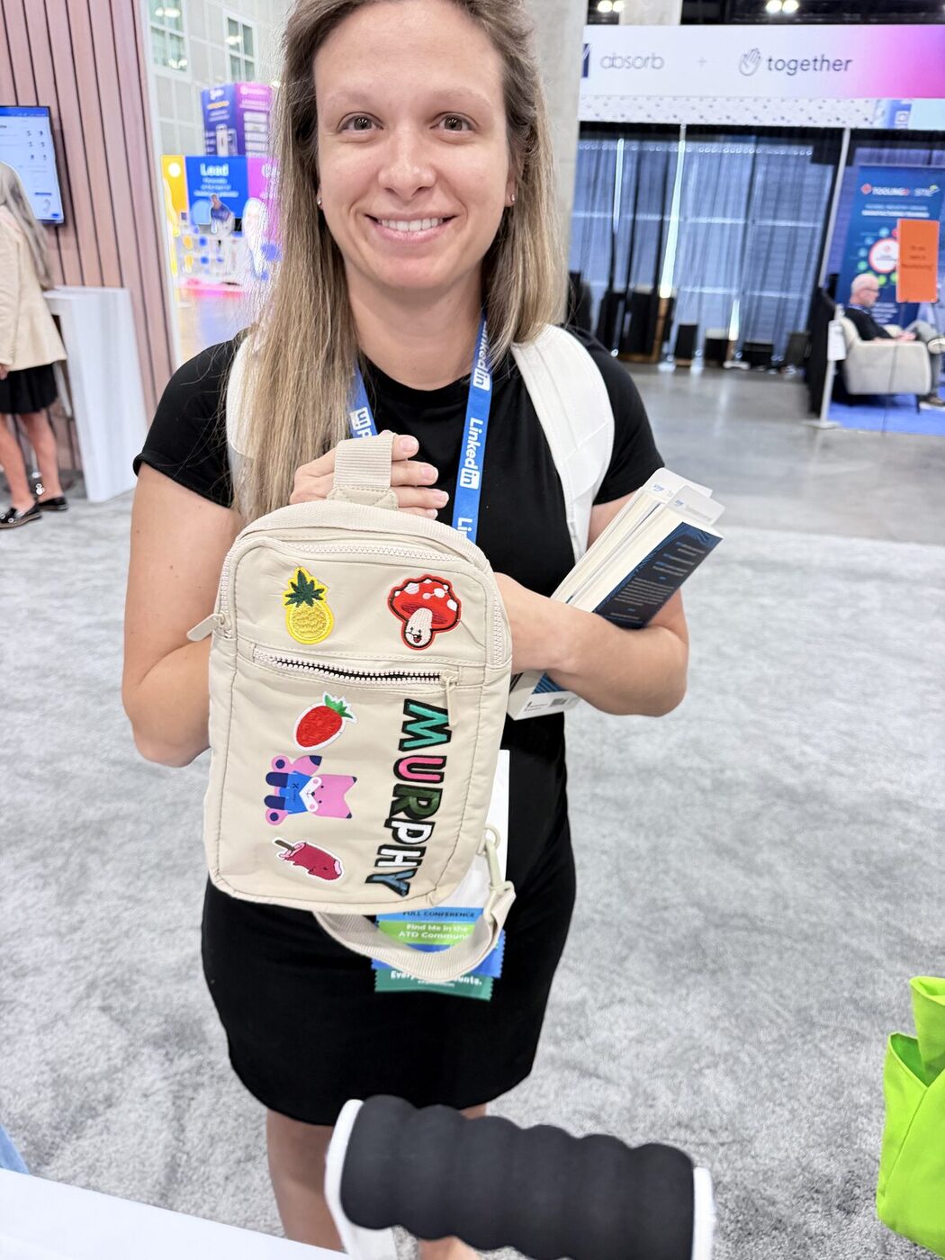Event guest holding a personalized canvas bag with patches at a conference booth
